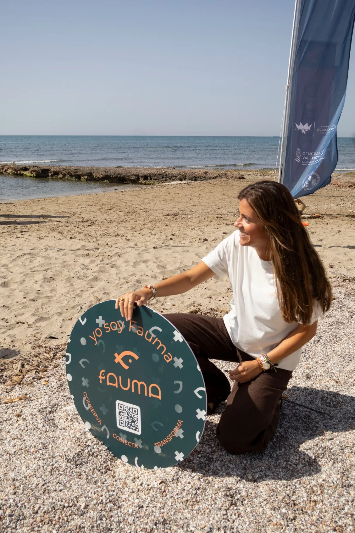 Chica sosteniendo el cartel Yo soy Fauma en la playa